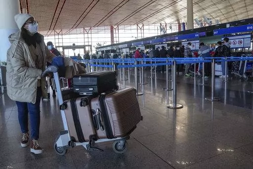 A masked traveller arrives at the international flight check in counter at the Beijing Capital International Airport in Beijing, Thursday, Dec. 29, 2022. Moves by the U.S., Japan and others to mandate COVID-19 tests for passengers arriving from China reflect global concern that new variants could emerge in its ongoing explosive outbreak — and the government may not inform the rest of the world quickly enough. (AP Photo/Andy Wong)