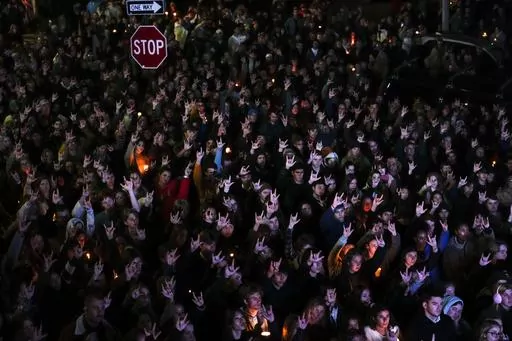 People sign "I love you" while gathered at a vigil for the victims of Wednesday's mass shootings, Oct. 29, 2023, outside the Basilica of Saints Peter and Paul in Lewiston, Maine. A commission investigating the shooting that killed 18 people is scheduled to hear from a police agency that had contact with the shooter before he committed the killings. Maine Gov. Janet Mills and Attorney General Aaron Frey assembled the commission to review the events that led up to the shootings at a bowling alley 