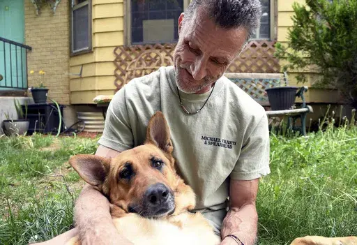 Simon Rubick, who sought help from PAWsitive Recovery while he was recovering from drug and alcohol addiction, holds his rescue dog Tonks in Aurora, Colo., on Monday, June 3, 2024. (AP Photo/Thomas Peipert)