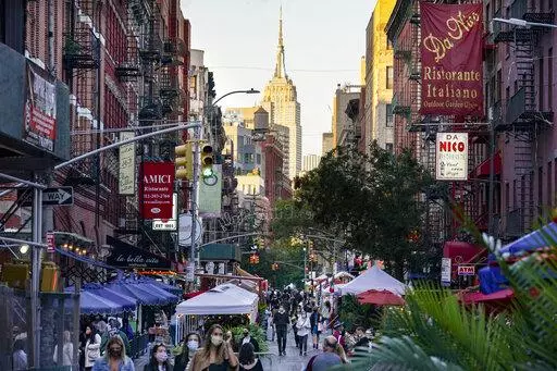 People walk through an area where restaurants operate outdoor spaces for dining that spread onto sidewalks and streets as part of continued COVID-19 economic impact mitigation efforts, Saturday, Oct. 3, 2020, in New York. As New York City forges ahead with its recovery, the pandemic is leaving lasting imprints, especially on city roadways: less room for cars and more space for people. (AP Photo/John Minchillo, File)