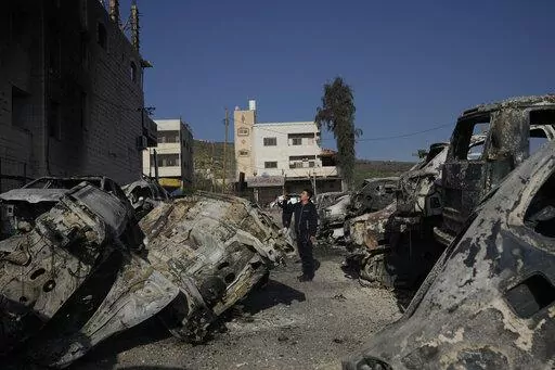 Palestinians take photos of burned cars in the town of Huwara, near the West Bank city of Nablus, Monday, Feb. 27, 2023. Scores of Israeli settlers went on a violent rampage in the northern West Bank, setting cars and homes on fire after two settlers were killed by a Palestinian gunman. Palestinian officials say one man was killed and four others were badly wounded. (AP Photo/Majdi Mohammed)