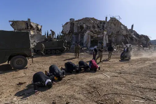 Lebanese men pray after they entered their destroyed hometown of Kfar Kila, southern Lebanon, Tuesday, Feb. 18, 2025. (AP Photo/Hassan Ammar)