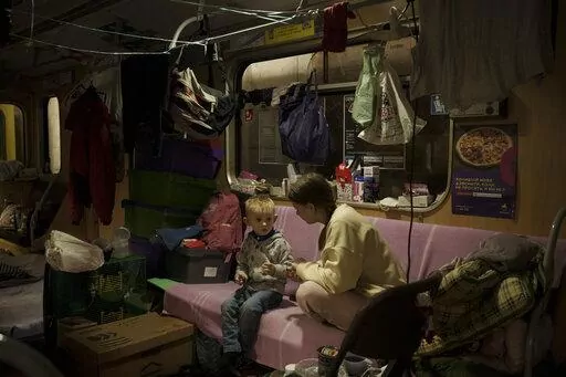 People sit inside a subway car, parked in a station being used as a bomb shelter, as Russian attacks continue in Kharkiv, Ukraine, Friday, March 25, 2022. (AP Photo/Felipe Dana)