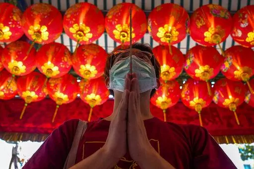 A person holds joss sticks while praying for good fortune on the eve of the Chinese Lunar New Year at Tai Hong Kong Shrine in Bangkok, Thailand, Monday, Jan. 31, 2022. The new year celebrations according to the lunar calendar will take place on Feb. 1. (AP Photo/Sakchai Lalit)