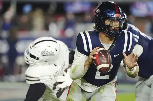 Mississippi quarterback Jaxson Dart (2) dodges a tackle-attempt by Mississippi State defensive lineman Trevion Williams, left, during the second half of an NCAA college football game, Friday, Nov. 29, 2024, in Oxford, Miss. (AP Photo/Rogelio V. Solis)