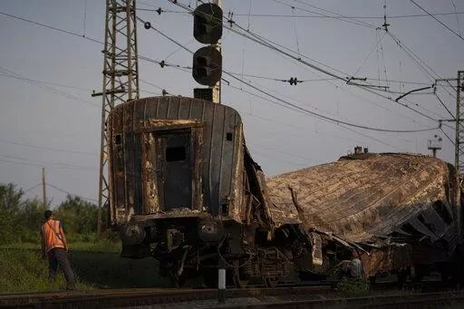 A railway worker looks at a heavily damaged train after a Russian attack on a train station Wednesday during Ukraine's Independence Day in the village Chaplyne, Ukraine, Thursday, Aug. 25, 2022. (AP Photo/Leo Correa)
