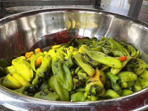 This July 12, 2021 image shows a large bowl of roasted green chile at a market in Hatch, N.M. Farmers say the season is shaping up to be a good one thanks to recent rain and cooler temperatures. There's nothing like the sweet smell of green chile roasting on an open flame. It permeates New Mexico every fall, wafting from roadside stands and grocery store parking lots, inducing immediate salivation and visions of mouth-watering culinary wonders laden with hot peppers. Democratic Sen. Bill Soules 