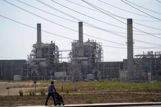 A man pushes a stroller near the AES power plant in Redondo Beach, Calif., Wednesday, Sept. 7, 2022. A record heat wave put California in a fossil fuel conundrum: The state has had to rely more heavily on natural gas to produce electricity and avoid power outages while Gov. Gavin Newsom's administration moves toward ending the use of oil and gas. (AP Photo/Jae C. Hong)