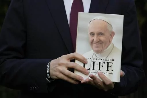 Italian journalist and writer Fabio Marchese Ragona holds a copy of "Life: My Story Through History" as he poses for a picture prior to the start of an interview with the Associated Press, in Rome, Thursday, March 13, 2024. Pope Francis says he has no plans to resign and isn't suffering from any health problems that would require doing so, in an autobiography, "Life: My Story Through History," which is being published Tuesday and written with Italian journalist Fabio Marchese Ragona. (AP Photo/G