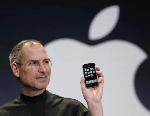 Apple CEO Steve Jobs holds up an Apple iPhone at the MacWorld Conference in San Francisco on Jan. 9, 2007. The iPhone introduced the convenience of touchscreens at the time that a physical keyboard was still all the rage on the top-selling smartphone – the BlackBerry – when Jobs first took out what was all-in-one computer, camera and music player out of his pocket in 2007. (AP Photo/Paul Sakuma, File)