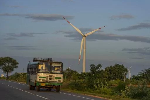 A bus drives past a windmill farm in Anantapur district, Andhra Pradesh, India, Sept 14, 2022. The key priority for India at the upcoming U.N. climate conference will be how to pay for the transition away from fossil fuels for energy and industries to meet temperature limit targets, according to a senior official who'll be part of the negotiations. (AP Photo/Rafiq Maqbool)