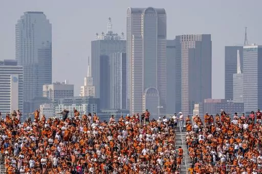 The Dallas skyline rises behind the Cotton Bowl stands as Texas fans watch during the first half of an NCAA college football game against Oklahoma at the Cotton Bowl, Saturday, Oct. 8, 2022, in Dallas. U.S. metropolitan areas increased their populations by almost half a percent last year in another sign that flight from urban areas during the first year of the pandemic either slowed down or reversed in its second year as people moved to Sunbelt metros in Texas and Florida by the tens of thousand