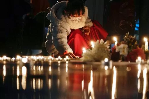 A girl lights candles at the site after the "Goddess of Democracy" statue, a memorial for those killed in the 1989 Tiananmen crackdown, was removed from the Chinese University of Hong Kong, Friday, Dec. 24, 2021. The university early Friday morning took down the statue that was based on a figure created by art students and brought to the square shortly before the crackdown in which hundreds of people were killed. (AP Photo/Vincent Yu)