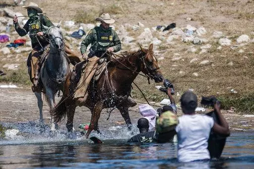 Mounted U.S. Border Patrol agents attempt to contain migrants as they cross the Rio Grande from Ciudad Acuña, Mexico, into Del Rio, Texas, Sept. 19, 2021. Border Patrol agents on horseback engaged in "unnecessary use of force" against non-threatening Haitian immigrants but didn't whip any with their reins, according to a federal investigation of chaotic scenes along the Texas-Mexico border last fall. (AP Photo/Felix Marquez, File)