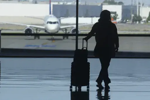 A holiday traveler looks out at a airplane at Salt Lake City International Airport, in Salt Lake City, July 3, 2024. (AP Photo/Rick Bowmer, File)