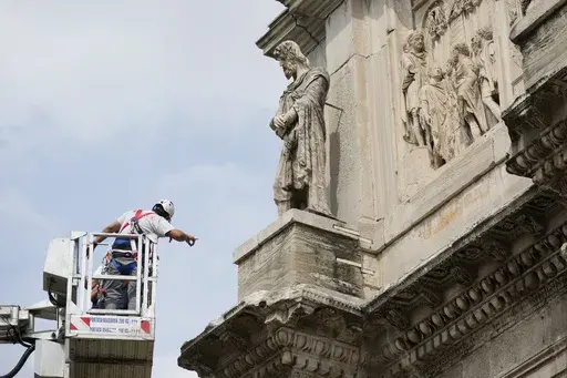 Workers inspect the 315 A.D Arch of Constantine, near the Colosseum, in Rome, Wednesday, Sept. 4, 2024, after lightning struck it during a storm Tuesday, Sept. 3, loosening fragments from the ancient Roman structure. (AP Photo/Andrew Medichini)