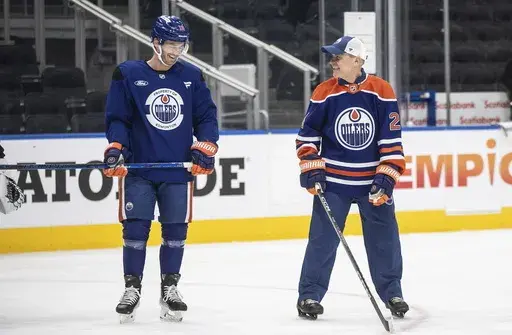 Canadian Prime Minister Mark Carney skates with Edmonton Oilers' Derek Ryan (10) at the NHL hockey team's practice during a visit to Edmonton, Alberta, Thursday, March 20, 2025. (Jason Franson/The Canadian Press via AP)