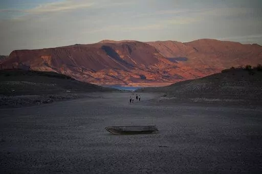 A formerly sunken boat sits on cracked earth hundreds of feet from what is now the shoreline on Lake Mead at the Lake Mead National Recreation Area, Monday, May 9, 2022, near Boulder City, Nev. Lake Mead is receding and Sin City is awash with mob lore after a second set of human remains emerged within a week from the depths of the drought-stricken Colorado River reservoir just a short drive from the Las Vegas Strip.  (AP Photo/John Locher)