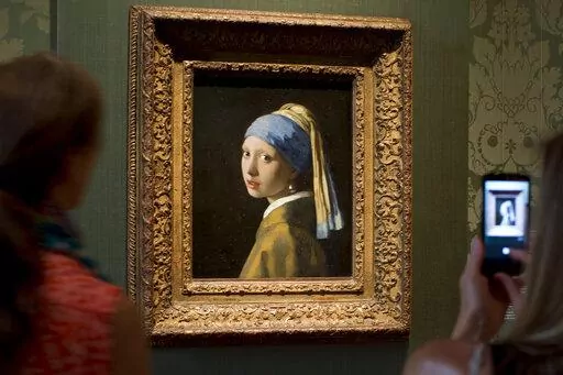 FILE- Visitors take pictures of Johannes Vermeer's Girl with a Pearl Earring (approx. 1665) during a preview for the press of the renovated Mauritshuis in The Hague, Netherlands, June 20, 2014. The Vermeer masterpiece “Girl with a Pearl Earring” has become the latest artwork targetted by climate activists in a protest at the Mauritshuis museum in The Hague on Thursday, Oct. 27, 2022. The museum did not immediately return calls and emails for comment after a video of the protest was posted on