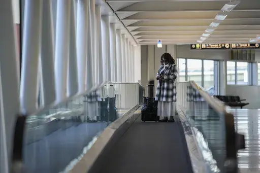 A traveler pauses to look at their phone, Monday, Nov. 25, 2024, at Baltimore/Washington International Thurgood Marshall Airport in Baltimore. (AP Photo/Stephanie Scarbrough)
