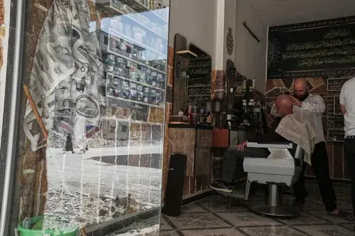 A barber shaves a client at his newly opened barbershop in Daraya, Syria, Monday, March 17, 2025. Part of rural Damascus, Daraya was one of the centers of the uprising against Bashar Assad and suffered killings and saw massive damage during fighting. (AP Photo/Omar Sanadiki)