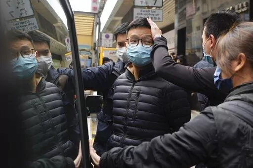 Editor of Stand News Patrick Lam, center, is escorted by police officers into a van after they searched evidence at his office in Hong Kong, Wednesday, Dec. 29, 2021. Hong Kong police raided the office of the online news outlet on Wednesday after arresting several people for conspiracy to publish a seditious publication. (AP Photo/Vincent Yu)