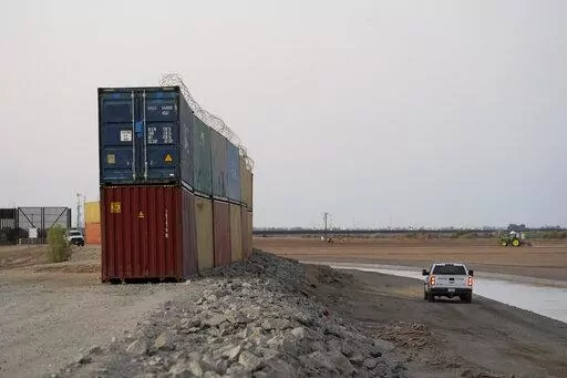 Border Patrol agents patrol along a line of shipping containers stacked near the border on Aug. 23, 2022, near Yuma, Ariz. The Cocopah Indian Tribe is welcoming the federal government's call for the state of Arizona to remove a series of double-stacked shipping containers placed along the U.S.-Mexico border near the desert city of Yuma, saying they are unauthorized and violate U.S. law. (AP Photo/Gregory Bull, File)