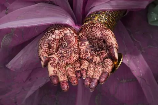 A Muslim woman holds out her hands painted with traditional "henna" as she performs an Eid al-Fitr prayer, marking the end of the fasting month of Ramadan, at the Badshahi mosque, in Lahore, Pakistan, Saturday, April, 22, 2023. (AP Photo/K.M. Chaudary)