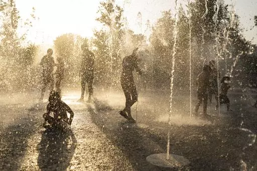 Children play with the water on a fountain during a heat wave, at Stavros Niarchos foundation Cultural Center in Athens, Friday, July 21, 2023. Heat in Greece is expected to grow worse during the weekend, approaching 44 Celsius (111 Fahrenheit) and the country will face one more heatwave episode by the end of July. (AP Photo/Petros Giannakouris)
