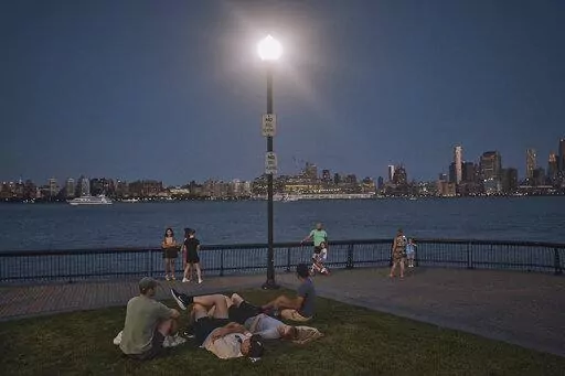 People spend time at the park at dusk during a summer heat wave, July 21, 2022, in Hoboken, N.J. The continental United States in July set a record for overnight warmth, providing little relief from the day’s sizzling heat for people, animals, plants and the electric grid, meteorologists said. (AP Photo/Andres Kudacki, File)