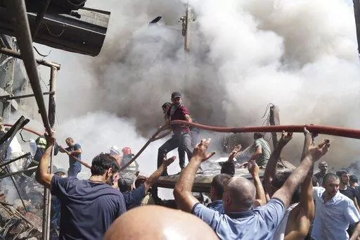 People help firefighters to deliver water to extinguish flames at Surmalu market about two kilometers (1.2 miles) south of the center Yerevan, Armenia, Sunday, Aug. 14, 2022. A strong explosion at a fireworks storage area has ripped through a market in Armenia's capital. At least one person has been killed and about 20 others have been injured. The blast on Sunday set off a large fire. (AP Photo/Daniel Bolshakov)