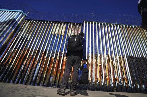 A migrant waits of the Mexican side of the border after United States Customs and Border Protection officers detained a couple of migrants crossing the US-Mexico border on the beach, in Tijuana, Mexico, Jan. 26, 2022. About 3 in 10 also worry that more immigration can cause native-born Americans to lose their economic, political and cultural influence, according to a poll by The Associated Press-NORC Center for Public Affairs Research. (AP Photo/Marco Ugarte, File)