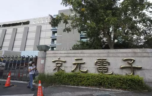 A worker walks past the logo of the factory of King Yuan Electronics Co. after work in Miaoli County, western Taiwan, May 9, 2024. In late April 2024, King Yuan Electronics Corp., a Taiwanese company specializing in semiconductor testing and packaging, said it was ending its two-decade-long run in mainland China by selling off its entire stake, worth $670 million, in its venture in the eastern Chinese city of Suzhou. (AP Photo/Chiang Ying-ying)