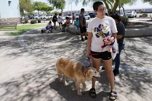 Rori Chang, of Glendale, Ariz., waits in line with her dog Ava to get microchipped at the Maricopa Country Animal Care & Control facility Friday, June 30, 2023, in Phoenix. Most of the U.S. may be looking forward to July Fourth celebrations for dazzling displays of fireworks or setting off firecrackers and poppers with their neighbors. Those with furry, four-legged family members — maybe not so much. They're searching for solutions to the Fourth of July anxiety that fireworks bring. (AP Photo/