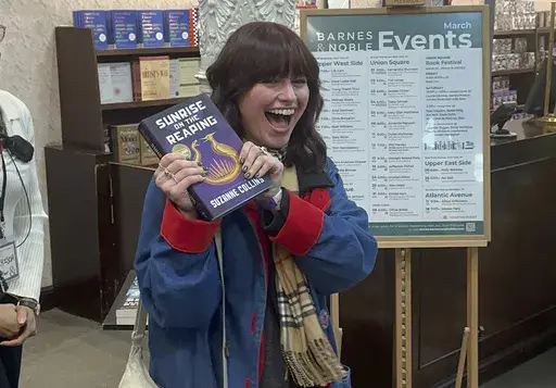 Ella Dolynchuk holds her copy of "Sunrise on the Reaping" by Suzanne Collins at a midnight launch party at Barnes & Noble bookstore in New York on Tuesday, March 18, 2025. (AP Photo/Hillel Italie)