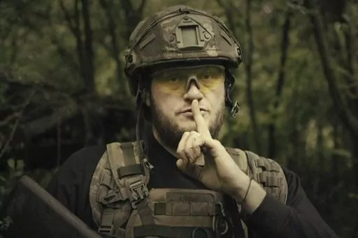 In this image made from video provided by Ukrainian Defense Ministry on Sunday, June 4, 2023, a Ukrainian soldier poses for the camera with his fingers to his lips, in an undisclosed location in Ukraine. A video released by the Ukrainian Defense Ministry on Sunday shows its military gesturing to silence suggesting that no formal announcement of a possible counter offensive against Russia will be made. The on-screen text of the video reads "Plans love silence. There will be no announcement of the