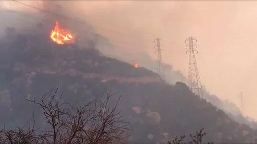 In this Saturday, Dec. 16, 2017, file image taken from video provided by the Santa Barbara County Fire Department, spot fires burn near power lines as heavy smoke fills the air from a wildfire in Santa Barbara, Calif. The nation's largest utility, Pacific Gas & Electric is poised to emerge from five years of criminal probation amid worries that it remains too dangerous to be trusted. Over the five years, the utility became an even more destructive force. More than 100 people have died and thousa