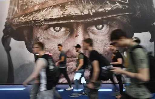Visitors passing an advertisement for the video game 'Call of Duty' at the Gamescom fair for computer games in Cologne, Germany, on Aug. 22, 2017. The European Union on Monday approved Microsoft’s $69 billion purchase of video game maker Activision Blizzard, deciding the deal won’t stifle competition for popular console titles like Call of Duty and accepting the U.S. tech company’s remedies to boost competition in cloud gaming. (AP Photo/Martin Meissner, File)