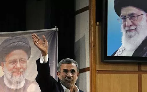 Iran's hard-line former President Mahmoud Ahmadinejad waves to the media as he leaves at the conclusion of a press briefing beside portraits of the Supreme Leader Ayatollah Ali Khamenei, top right, and the late President Ebrahim Raisi after registering his name as a candidate for the June 28 presidential election at the Interior Ministry, in Tehran, Iran, Sunday, June 2, 2024. Ahmadinejad registered Sunday as a possible candidate for the presidential election, seeking to regain the country's top