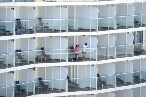 Passengers look out from the Spectrum of the Seas cruise ship docked at Kai Tak cruise terminal in Hong Kong Wednesday, Jan. 5, 2022. Thousands of passengers were being held Wednesday on the cruise ship in Hong Kong for coronavirus testing after health authorities said nine passengers were linked to a recent omicron cluster and ordered the ship to turn back. (AP Photo/Vincent Yu)