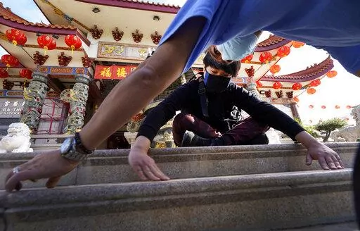Volunteers, Alex Koi, foreground, and his son Lipsun Koi, 20, help install anti-slip tape on the front steps of the Thien Hau Temple ahead of the crowds expected for the Lunar New Year of the Tiger celebrations in the Chinatown district of Los Angeles, Friday, Jan. 28, 2022. The Lunar New Year of the Tiger celebrations will occur on Feb. 1, amid warnings against travel and large gatherings due to COVID-19. (AP Photo/Damian Dovarganes)