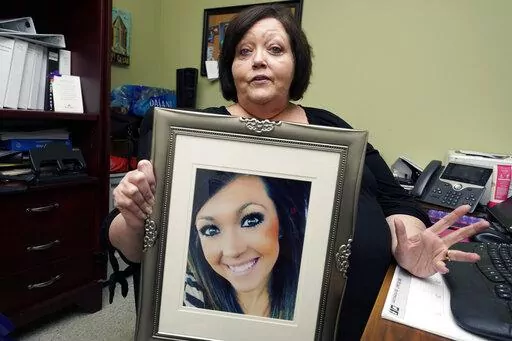 CORRECTS TO DELETE THE MIDDLE NAME AND SAY HARBOUR WAS A VICTIM - Denise Spears holds a portrait of her late step-daughter Marsha Harbour, in her Meridian, Miss., office, Tuesday, April 12, 2022. Although Marsha's husband, Truitt Pace, admitted killing his wife, he was free on bond while court proceedings were partially held up because the Mississippi Medical Examiner's Office autopsy report was delayed for a year, and the trial got held up further because of the pandemic and other factors. Harb
