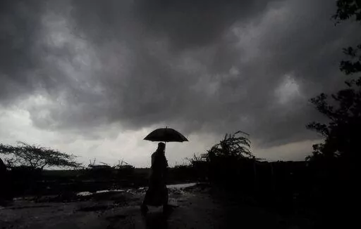A villager holds an umbrella as dark clouds loom over Balasore district in Odisha, India, Tuesday, May 25, 2021, ahead of a powerful storm barreling toward the eastern coast. When it comes to measuring global warming, it’s not just the heat, it’s the humidity that matters in dangerous climate extremes, according to a study released on Monday, Jan. 31, 2022, in the Proceedings of the National Academy of Sciences in the U.S. (AP Photo/File)