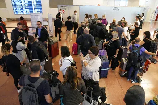 Foreign travelers gather upon arrival at the Haneda International Airport Tuesday, Oct. 11, 2022, in Tokyo. Japan's strict border restrictions are eased, allowing tourists to easily enter for the first time since the start of the COVID-19 pandemic. Independent tourists are again welcomed, not just those traveling with authorized groups. (AP Photo/Eugene Hoshiko)