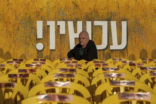 Luis Har, who was rescued from Hamas captivity in an Israeli raid last year, poses for a photo surrounded by empty chairs with photographs of other hostages' eyes, in Tel Aviv, Israel, Monday, Jan. 6, 2025. (AP Photo/Ohad Zwigenberg)