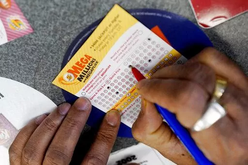A customer fills out a Mega Millions lottery ticket at a convenience store in Northbrook, Ill., on Jan. 6, 2021. The holiday shopping season, for Mega Millions lottery ticket buyers, at least, is ramping up as officials say the estimated jackpot for the drawing the night of Tuesday, Dec. 27, 2022, has surpassed half a billion dollars. (AP Photo/Nam Y. Huh, File)