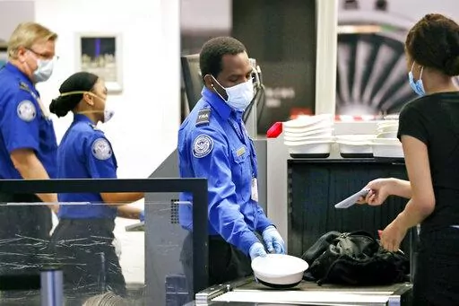 Transportation Security Administration officers process passengers at a security screening area at Seattle-Tacoma International Airport in SeaTac, Wash., on May 18, 2020. With a surge in guns being discovered at airport checkpoints, some security experts are suggesting higher fines and even putting violators on a no-fly list to prevent guns from getting on planes. (AP Photo/Elaine Thompson, File)