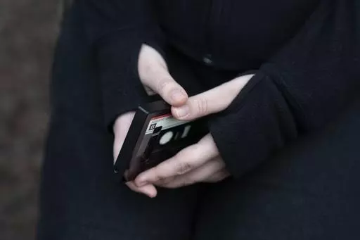 A teenager holds her phone as she sits for a portrait near her home in Illinois, on Friday, March 24, 2023. The U.S. Surgeon General is warning there is not enough evidence to show that social media is safe for young people — and is calling on tech companies, parents and caregivers to take "immediate action to protect kids now." (AP Photo Erin Hooley, File)