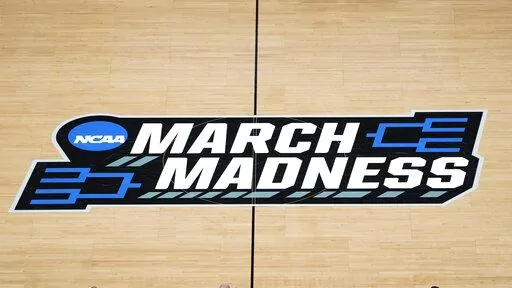 FILE -The March Madness logo is shown on the court during the first half of a men's college basketball game in the first round of the NCAA tournament at Bankers Life Fieldhouse in Indianapolis, Saturday, March 20, 2021. Kansas, Villanova, North Carolina and Duke will play in the first Final Four to take place under the new world of “name, image and likeness” endorsements in college sports. It allows college players to earn money through endorsements. (AP Photo/Paul Sancya, File)