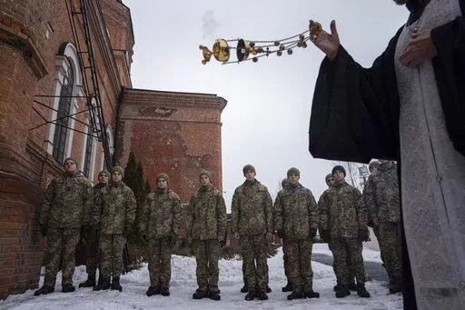 An Orthodox priest blesses Ukrainian Military Air Force University cadets after a monthly memorial service for soldiers who were killed during the fighting against Russia-backed separatists in eastern Ukraine, in Kharkiv, Ukraine, Thursday, Feb. 3, 2022. Russia maintains it has no intention to attack its neighbor, but demands that NATO won't expand to Ukraine and other ex-Soviet nations or deploy weapons there. It also wants the alliance to roll back its deployments to Eastern Europe. (AP Photo/